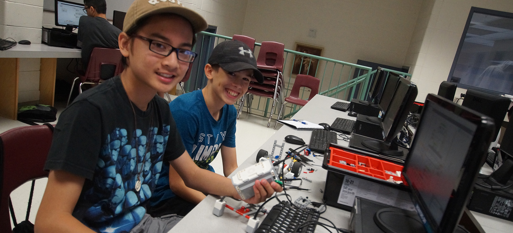 Two male students on computer and working on their robot